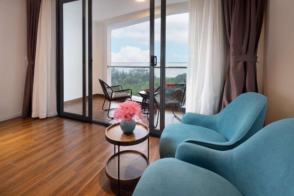 后川Le Palmier Ho Tram Resort的客厅配有蓝色椅子和鲜花桌