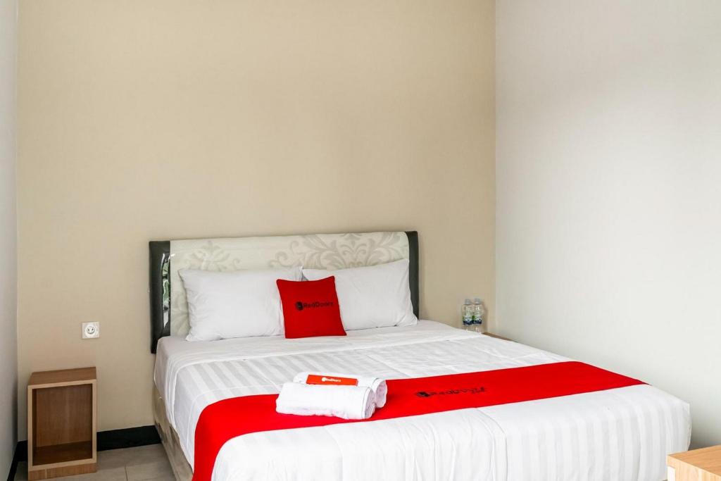 雅加达RedDoorz near Puri Indah Lippo Mall 2的一间卧室配有一张红色枕头的床