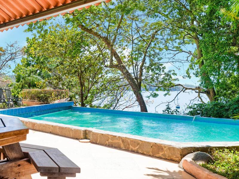 博卡奇卡Boca Chica BnB at Gone Fishing Panama Resort的一座大游泳池,位于一个树木繁茂的庭院内