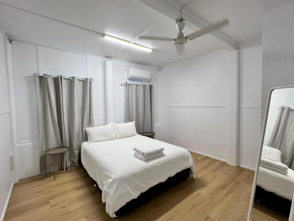 汤斯维尔Townsville Suites的白色卧室配有床和镜子