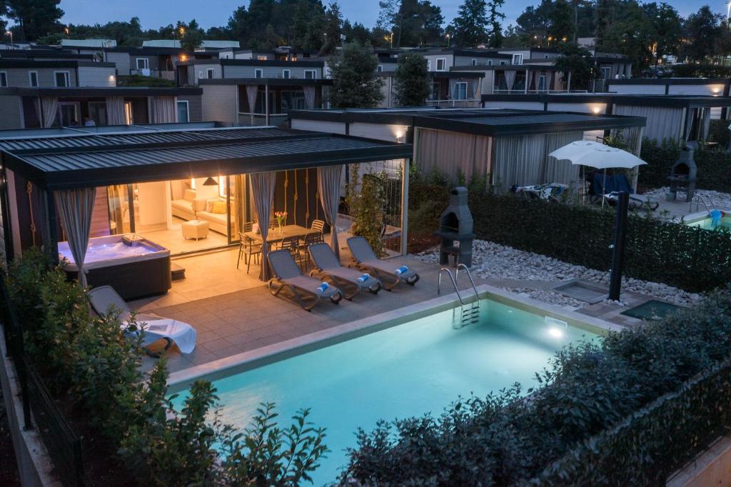 波雷奇Premium Camping Homes Santa Marina, Lanterna的后院的游泳池配有椅子和遮阳伞