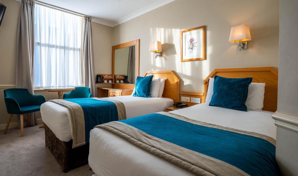 都柏林哈考特酒店的两张位于酒店客房的床,配有蓝色枕头