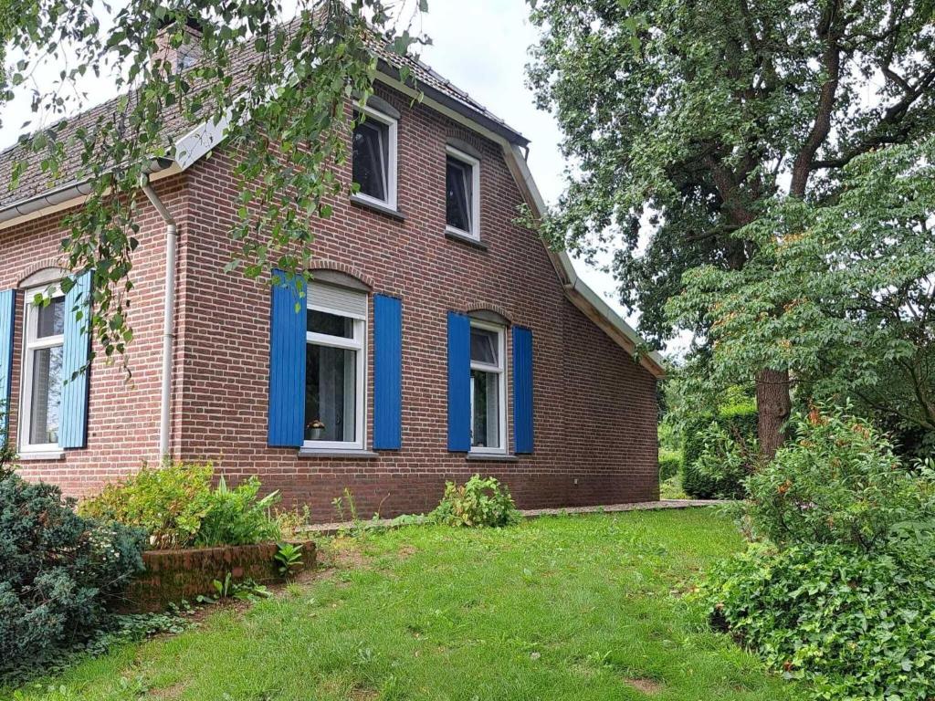 HapsPleasant Holiday Home in Haps with garden的一座带蓝色窗户和庭院的老砖屋