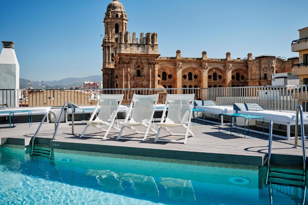 马拉加莫里纳拉里欧酒店的一组椅子坐在泳池旁的甲板上