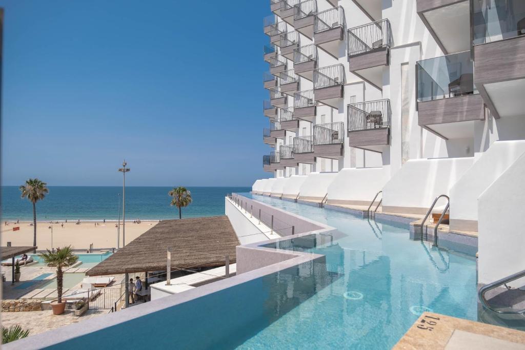 加的斯Cádiz Bahía by QHotels的享有酒店外景,设有游泳池和海滩