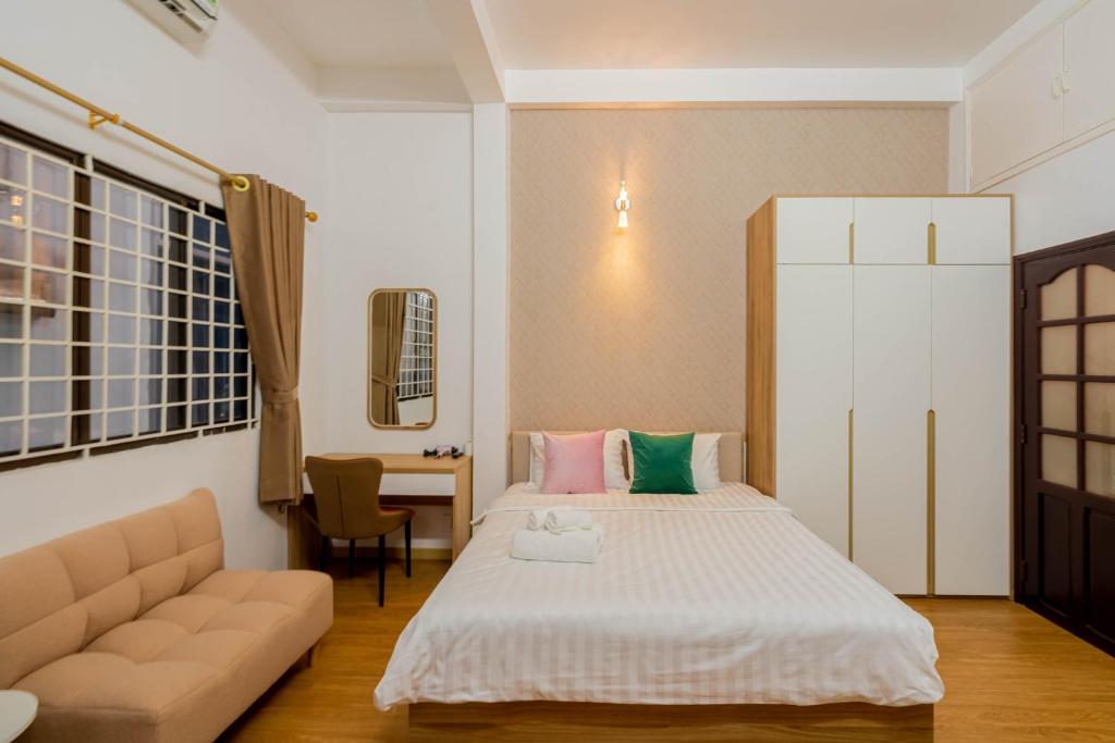 胡志明市Kansas Hotel & Apartment - Notre Dame的一间卧室配有一张床、一张沙发和一张桌子