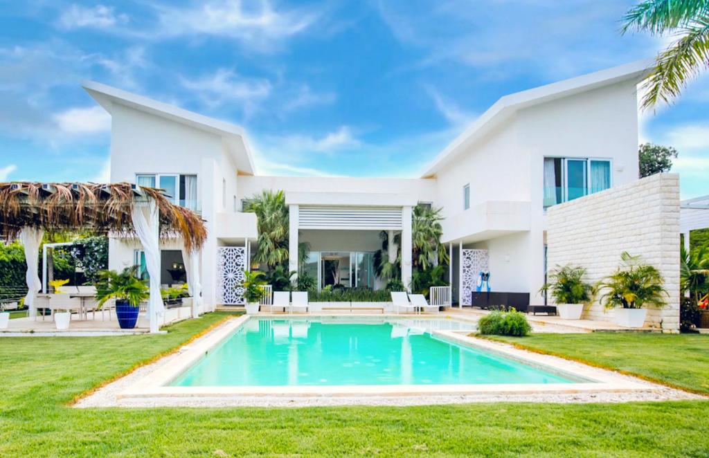 蓬塔卡纳Tranquil Lakefront 5-Bedroom Villa with Cook, Maid, Golf Cart, and Beach Access in Punta Cana的一座白色的房子,前面设有一个游泳池