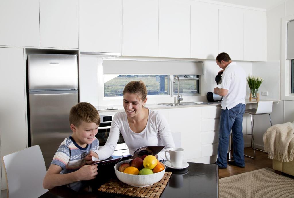 达博Savannah Cabins, Taronga Western Plains Zoo的妇女和儿童在厨房里吃一碗水果