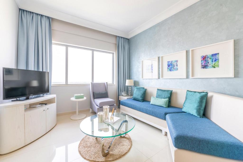 迪拜Downtown Luxury - 5 star Hotel Facilities - 5 min walk to Dubai Mall的客厅配有蓝色的沙发和电视