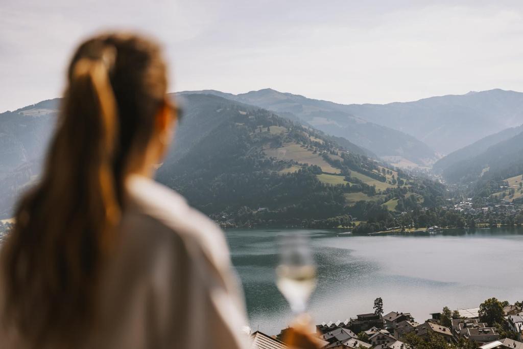 滨湖采尔Nikolaus by AvenidA Panoramic Wellness Suites的一边欣赏湖泊一边一边喝着葡萄酒