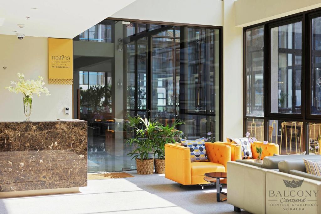 是拉差是拉差阳台庭院公寓式酒店及服务式公寓的大堂设有橙色家具和窗户。