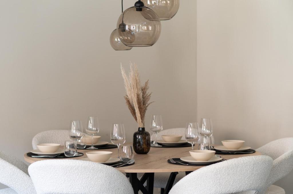 布鲁日Gastenkamers Ten Huyze Marchandise的餐桌、白色椅子和带玻璃杯的桌子