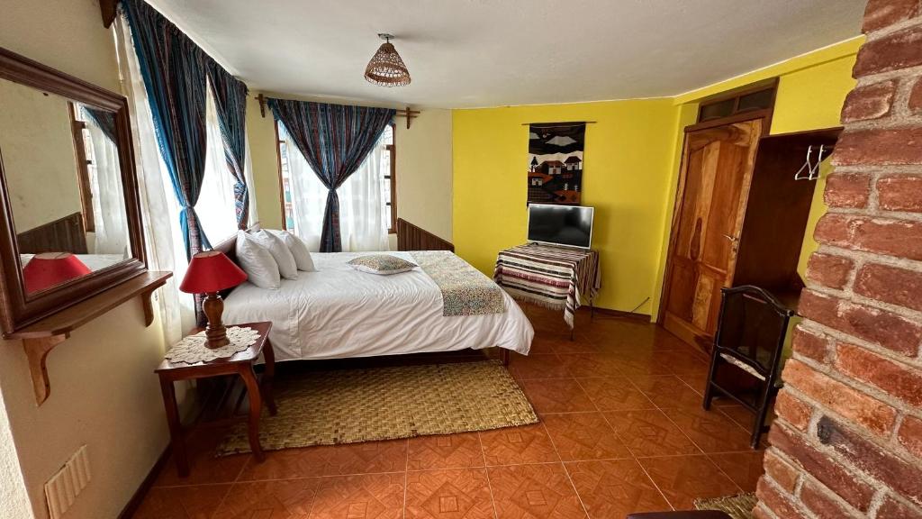 巴尼奥斯东德伊万酒店的一间卧室配有一张黄色墙壁的床和电视