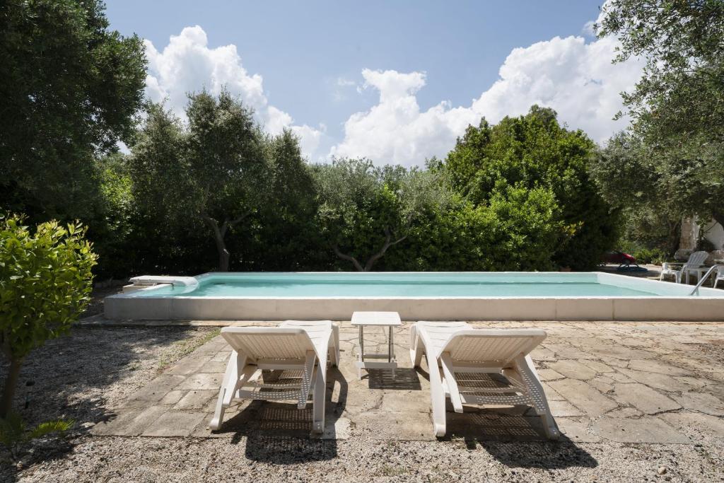 奥斯图尼Buenaventura House by Typney的一个带2把躺椅和桌子的游泳池
