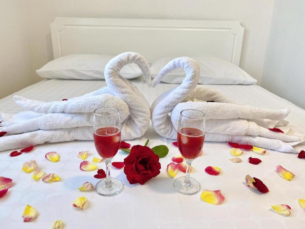 伏罗拉Arlind's Apartaments的床上有两条天鹅毛巾和两杯葡萄酒