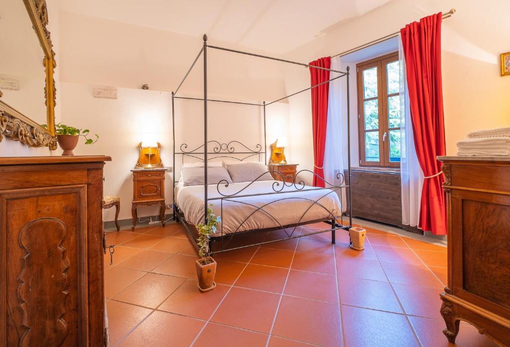 RustigazzoVeleia Romana B&B的一间卧室配有天蓬床和红色窗帘