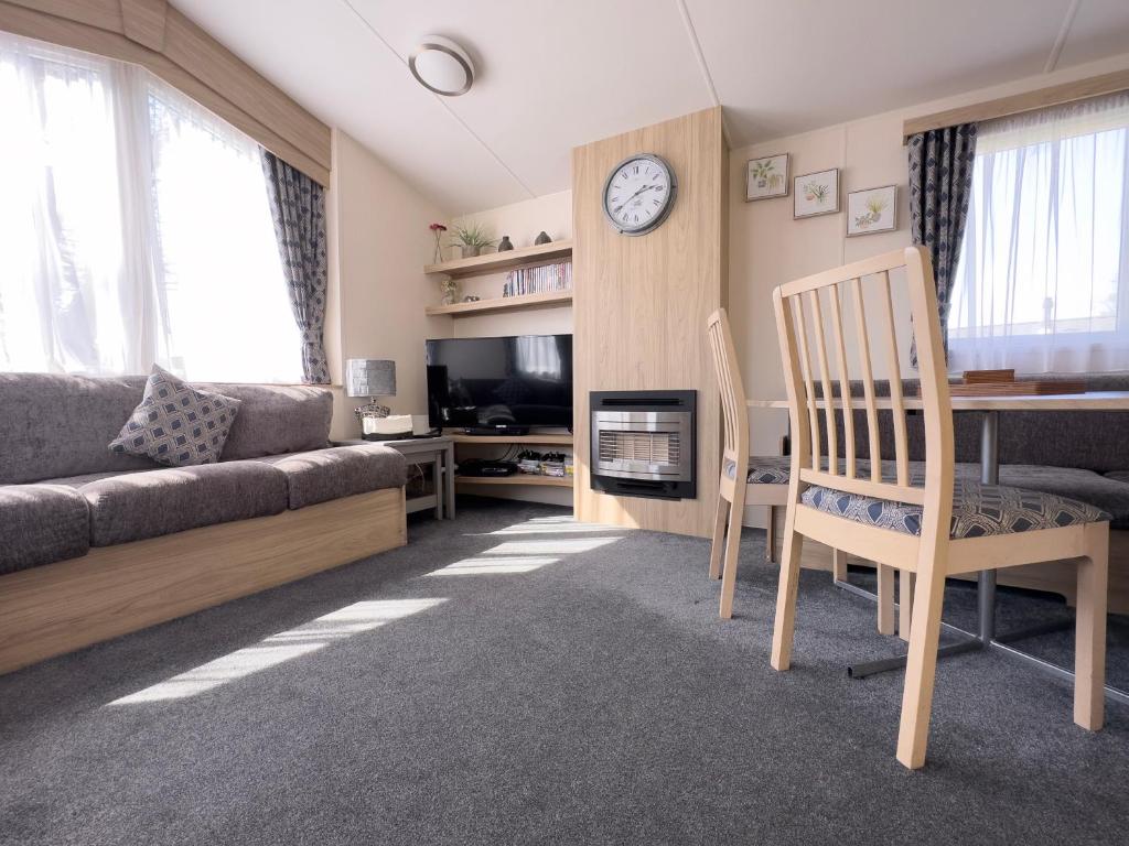 塞顿港Edinburgh - Seton Sands-Salsa Caravan-Pet Friendly的带沙发、桌子和时钟的客厅