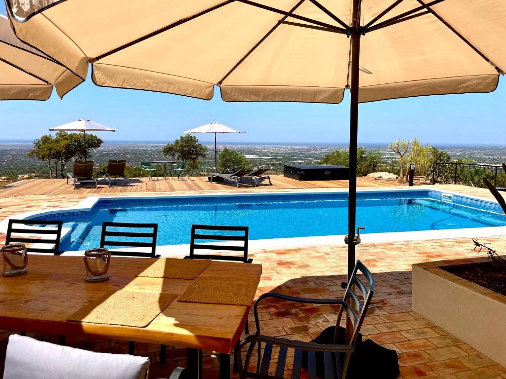 埃斯托伊Fantastic villa with panoramic coastal & sea views的游泳池旁带遮阳伞的桌子