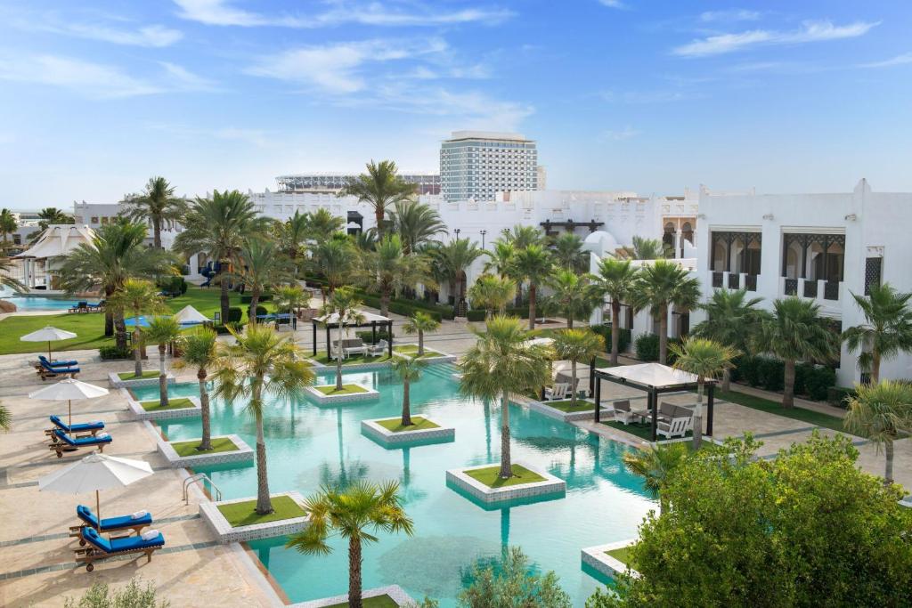 多哈Sharq Village & Spa, a Ritz-Carlton Hotel的享有棕榈树和建筑泳池的空中景致