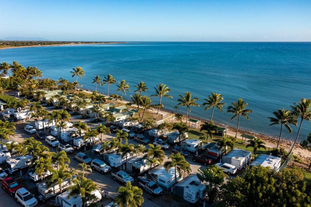 鲍恩NRMA Bowen Beachfront Holiday Park的享有棕榈树停车场和大海的空中景致