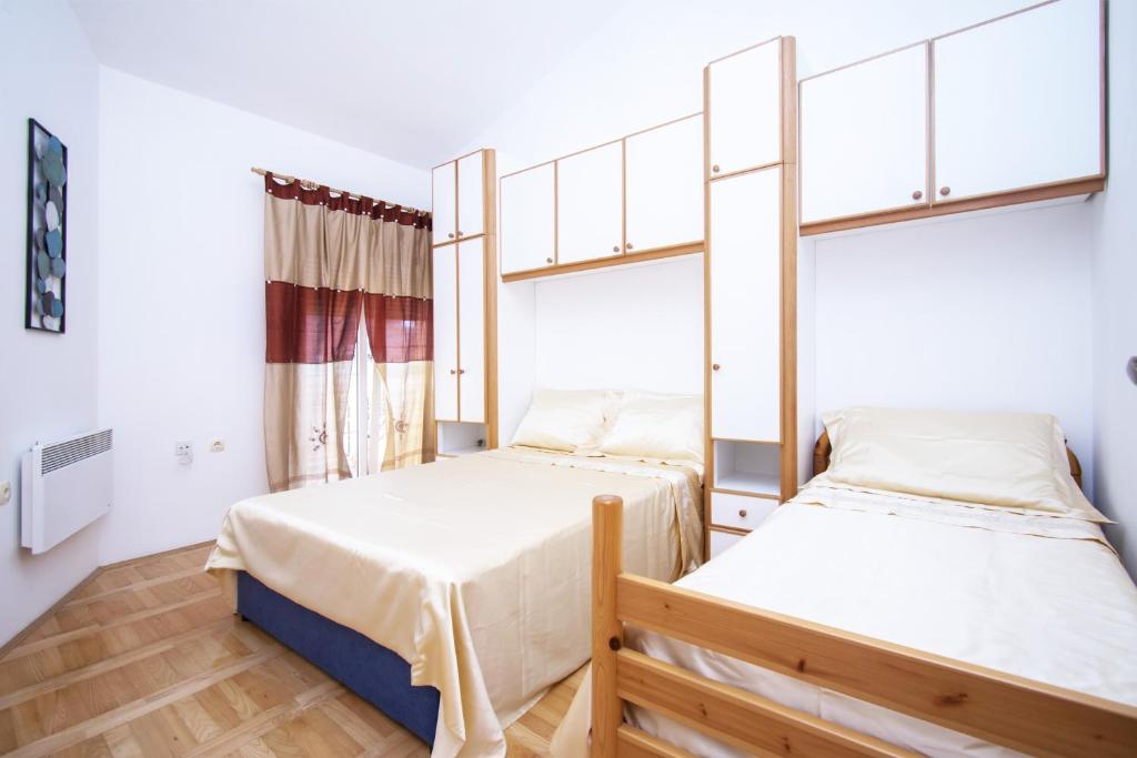 希贝尼克Seaside holiday house Jadrtovac, Sibenik - 16468的一间卧室设有两张床和窗户。