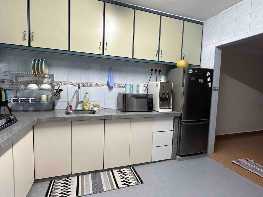 亚依淡AAA Homestay Georgetown Penang的厨房配有白色橱柜和黑色冰箱。