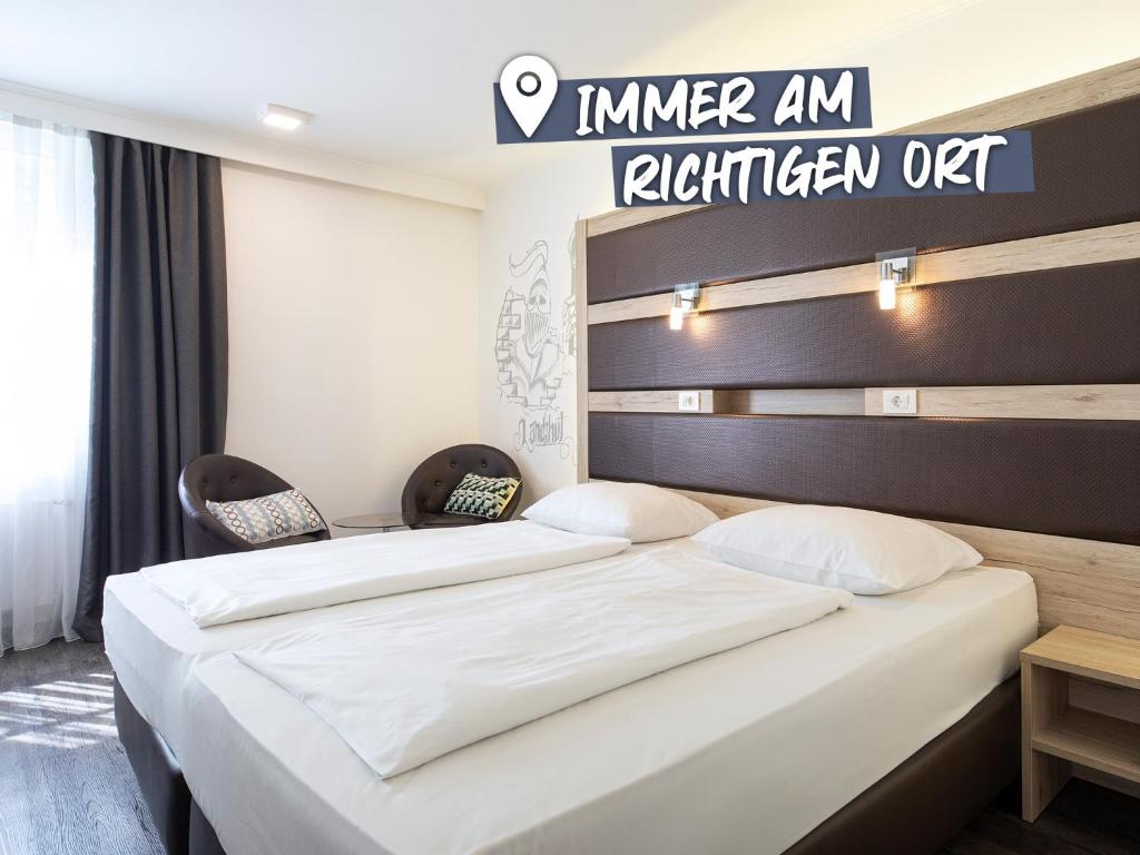 兰茨胡特ACHAT Hotel Kaiserhof Landshut的酒店客房,设有两张床和标志