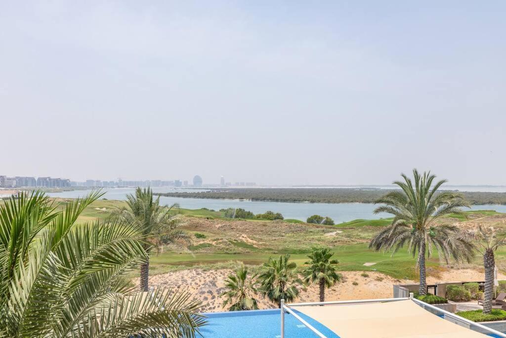 阿布扎比Casa Noera, Yas Island 324的享有棕榈树高尔夫球场和游泳池的景色