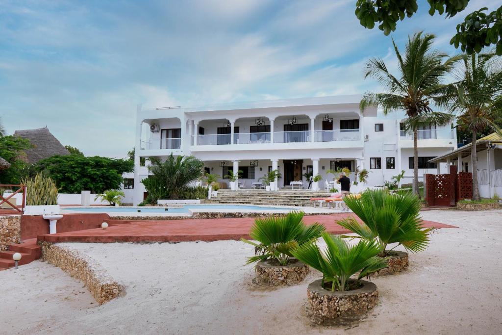 马林迪Met Beach Resort Malindi的一座白色的大建筑,前面有棕榈树