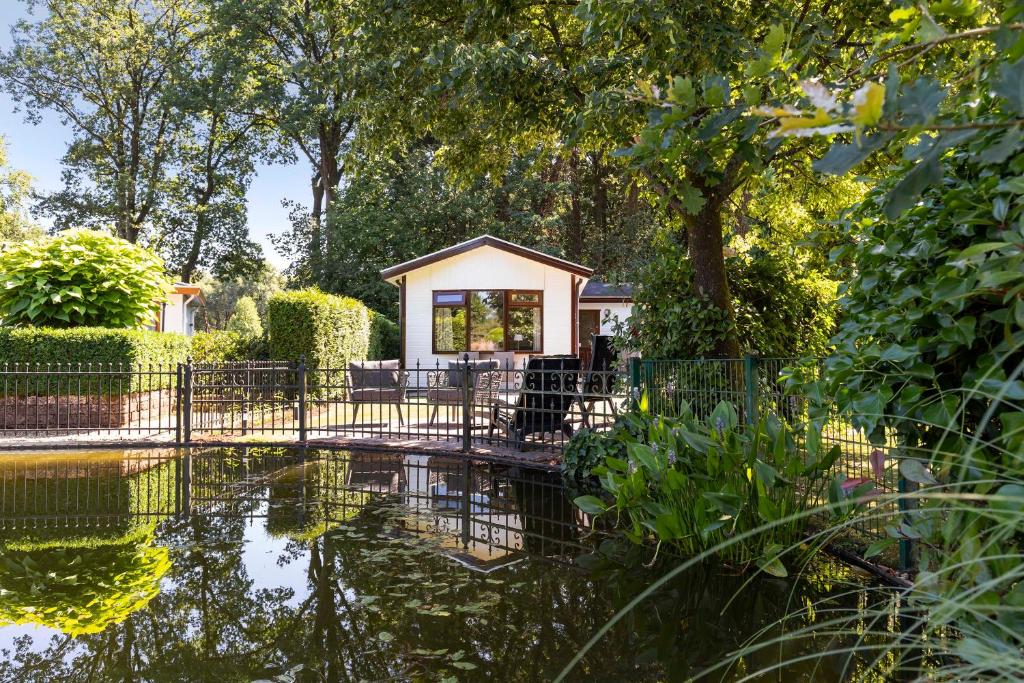 KootwijkHuize Bosrijk aan het water的前面有池塘的房子