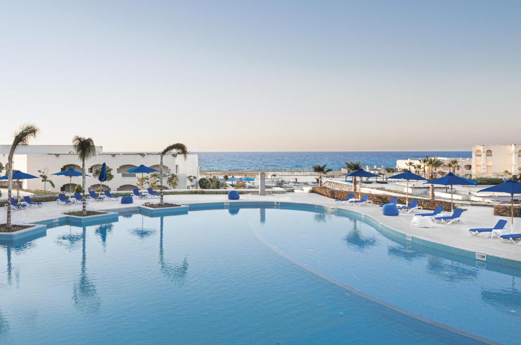 马特鲁港Cleopatra Luxury Resort Sidi Heneish - North Coast的一个带椅子和遮阳伞的大型游泳池,并享有海景。