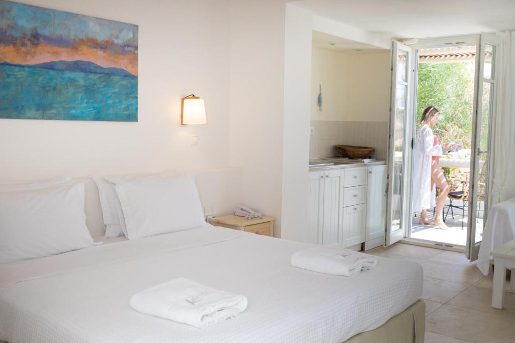 阿吉奥斯普罗科皮奥斯Kavos Hotel Naxos的一间白色卧室,配有床,外面有一位女士