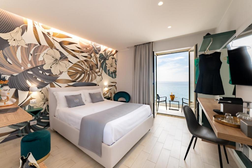 贾迪尼-纳克索斯Naxos Marina Bay的一间带一张床和一张书桌的卧室以及一个阳台