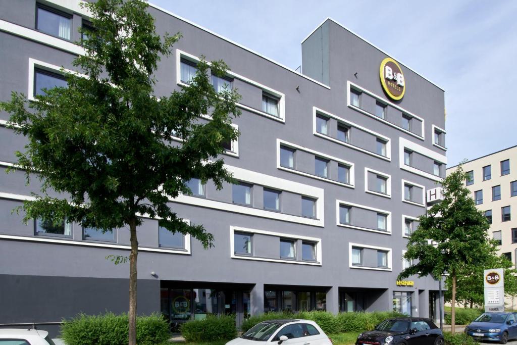 海德堡海德堡住宿加早餐酒店的一座灰色的大建筑,前面有汽车停放