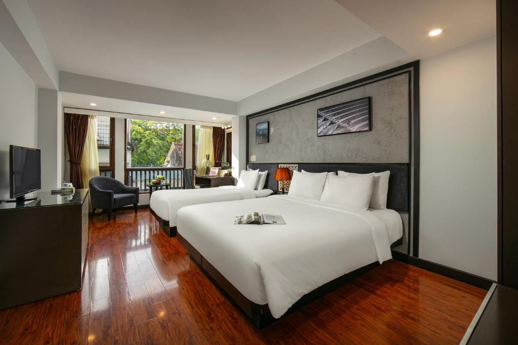 河内Hanoi La Palm Premier Hotel & Spa的酒店客房配有两张床和一张书桌