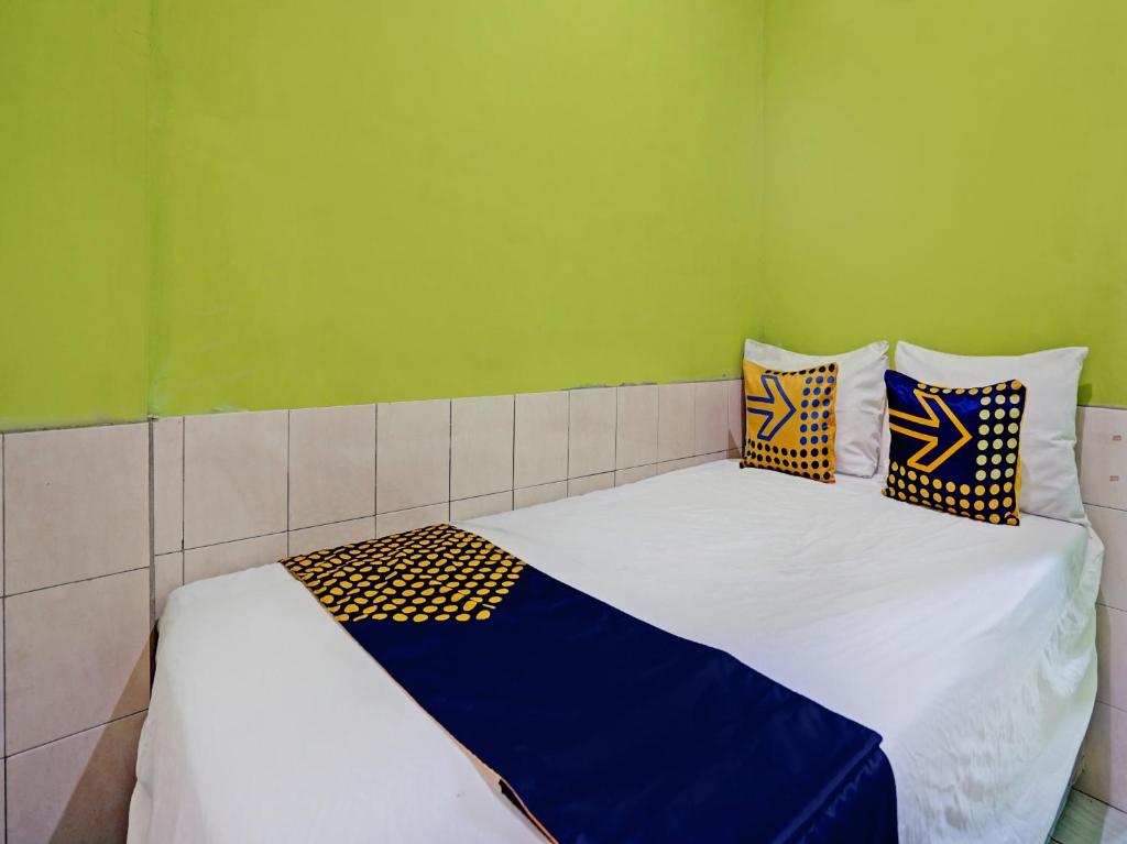 泗水OYO Life 92653 Homestay Griya Nautika Syariah的一间卧室配有白色的床和蓝色和黄色枕头