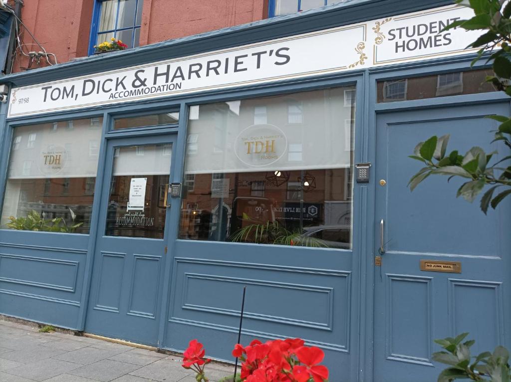 都柏林Tom Dick and Harriet's Accommodation的前方有蓝色门和红色鲜花的商店