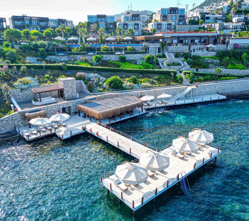亚力卡瓦克Allium Bodrum Resort & Spa的水中带椅子和遮阳伞的码头