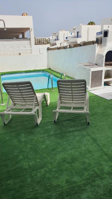 普拉亚布兰卡Marina Lucky的两个长椅坐在游泳池旁的草地上
