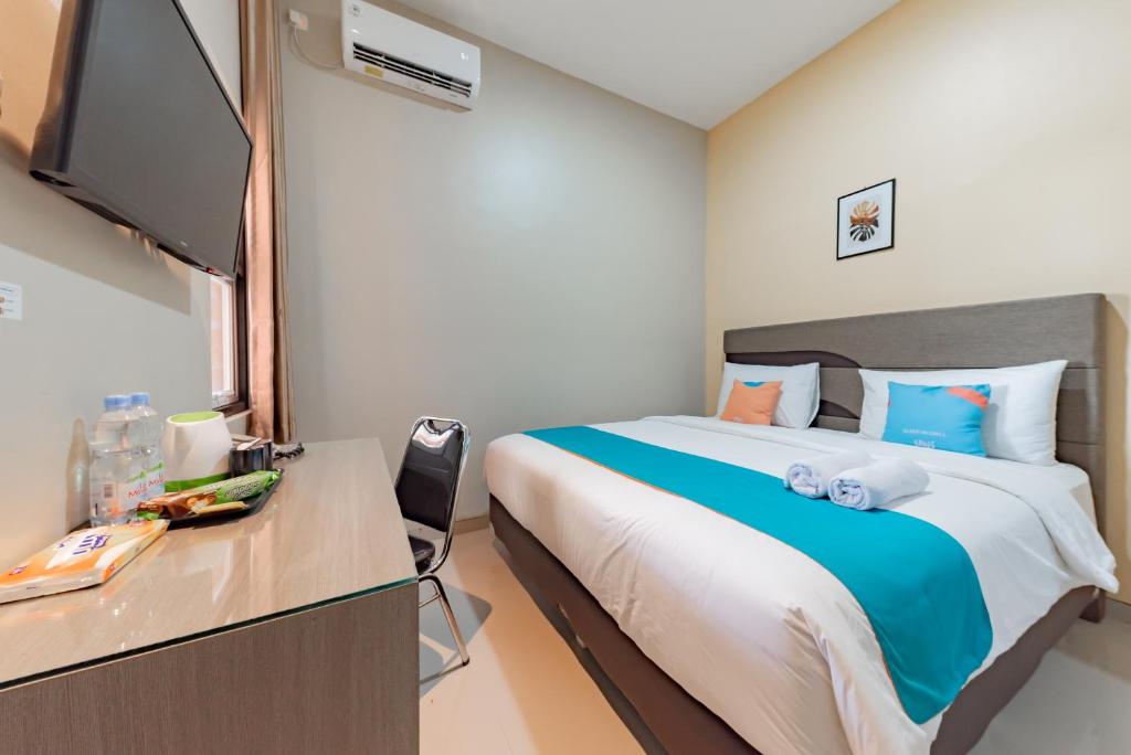 TanjungredepSans Hotel Berau Square的一间卧室配有一张床和一张书桌及电视