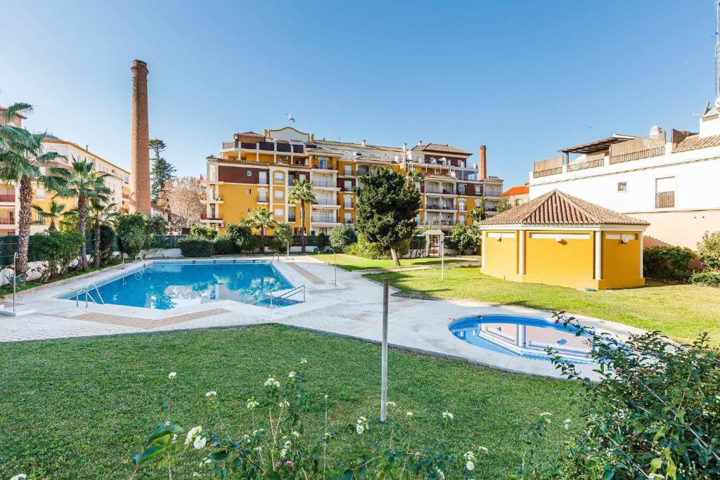 托雷德尔马尔Apartamento Azucarera Beach Torre del Mar的一座位于庭院内的游泳池,其建筑背景为: