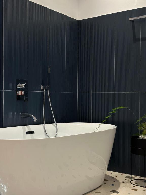 莱什Hotel Restaurant Natyra e Qetë的浴室铺有黑色瓷砖,配有白色浴缸。