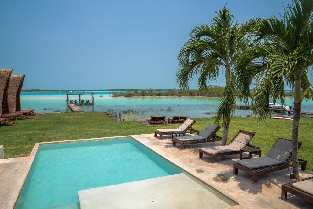 巴卡拉尔Hotel CasaBakal - A pie de Laguna - Bacalar的一个带椅子的游泳池,享有水景