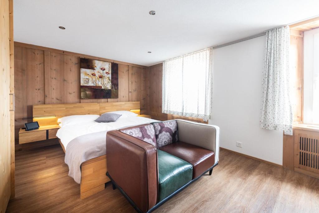 LenzLa Tgoma - Hotel & Restaurant的一间卧室配有一张床和一张皮椅