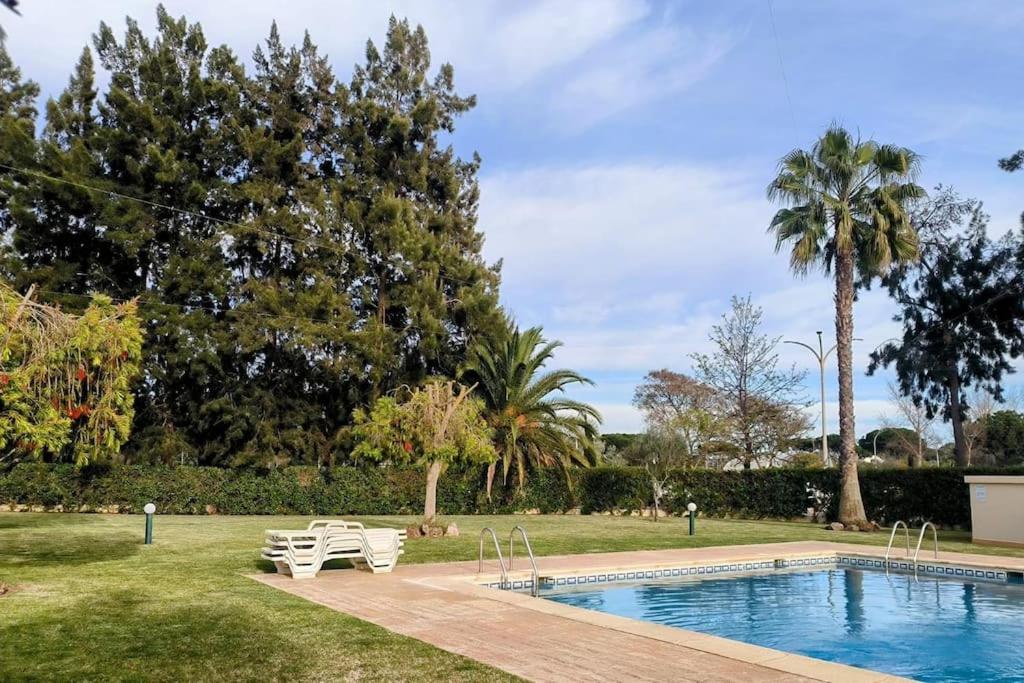 奎特里拉Casa das Mélias的公园内的游泳池,有两把白色的椅子和树木