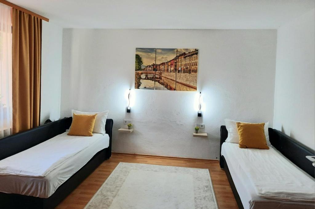 萨拉热窝Apartman Kovaci的一间设有两张床的客房,墙上挂着一幅画