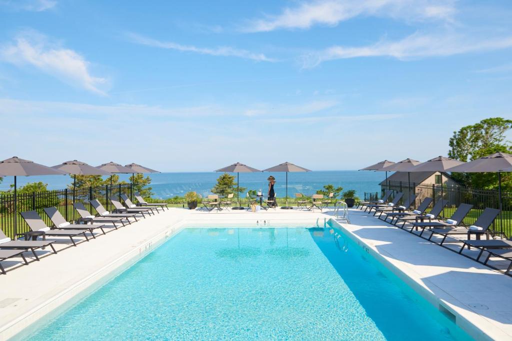 格林波特Hotel Moraine的一个带椅子的游泳池,背景是大海