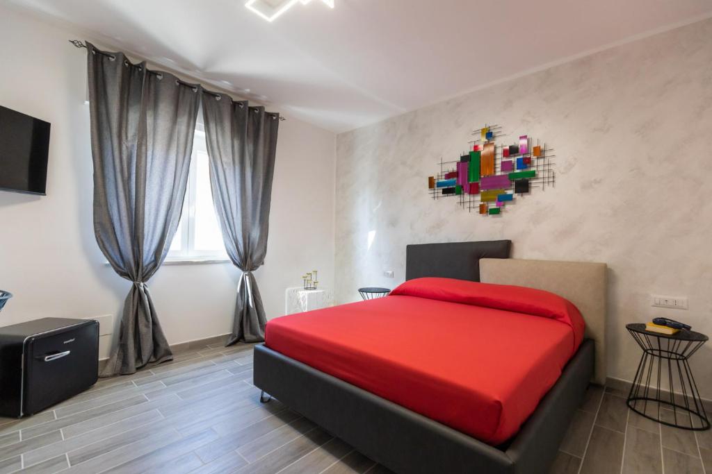 圣多米尼卡Residenza Saint Tropez的卧室配有红色的床,墙上挂着色彩缤纷的绘画作品