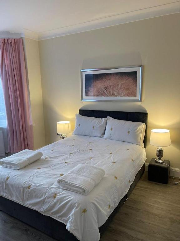 伍德福德格林4 Bed Family Home的一间卧室配有一张带两盏灯的大型白色床。