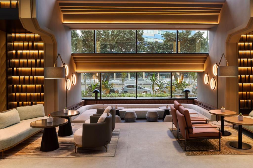 卡萨布兰卡卡萨布兰卡喜来登酒店的大堂配有沙发和桌子,设有大窗户。